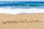 Word Vacation Written In Sand Of Beach At Sea Stock Photo