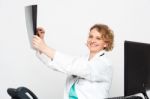 Smiling Doctor Looking At Scanned X-ray Report Stock Photo