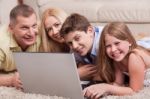 Domestic Family Lying In Living Room With Lap Top Stock Photo