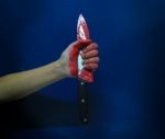 A Bloody Hand Holding A Large Blood Covered Knife Stock Photo