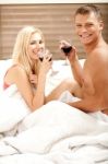 Couple Sharing A Drink In Bedroom Stock Photo