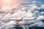 Airplane Flying Above Clouds In Sunlight Stock Photo