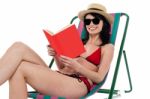 Enticing Bikini Model On A Deckchair Reading A Book Stock Photo