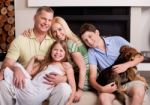 Happy Domestic Family Sitting In Living Room With Dog Stock Photo