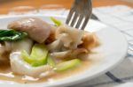 Rad Na, Famous Thai Chinese Style Wide Rice Noodle Dish With Tasty Tender Pork With Thick Gravy Sauce. Close Up With Fork Stock Photo