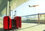 Stack Of Traveling Luggage In Airport Terminal And Passenger Plane Flying Over Sky Stock Photo