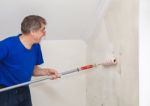Elderly Worker Painting Wall With Glue Stock Photo