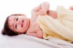 Little Smiling Baby Lying In White Towel And Wrapped With Yellow Towel Stock Photo