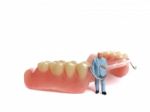 Miniature Elderly Standing On Removable Denture, On White Background. Dental Health Concept Stock Photo