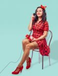 Smiling Young Pinup Woman Sitting On A Chair And Talking On Phon Stock Photo
