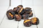 Hot Toasted Chestnuts On White Wooden Background Stock Photo