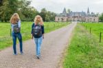 Two Girls Walking On Road Leading To Castle Stock Photo