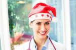 Happy Female Doctor Wearing Santa Hat Stock Photo