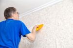 Man Smoothing The Wallpaper With A Spatula Stock Photo