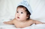 Sweet Newborn Baby In Blue Bobble Hat Lies On Bed Stock Photo