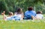 Happy Young Family Lying On Grass Stock Photo