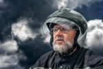 Portrait Of Elderly Motorcyclist On Gloomy Dark Cloudy Day Stock Photo