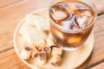 Glass Of Black Iced Coffee With Some Snack Stock Photo