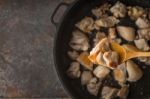 Fried Chicken In The Wooden Spoon With Blurred Pan Stock Photo