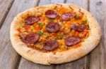 Delicious Baked Salami Pizza Served On Rustic Wooden Table Stock Photo