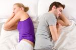 Couple Lying In Bed Back-to-Back Stock Photo