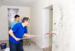 Worker Painting Wall With Background Glue For A Wallpaper Stock Photo