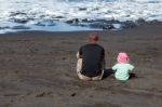 Dad And Daughter Watching The Waves Stock Photo