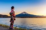 Asian Woman Wearing Japanese Traditional Kimono At Fuji Mountain. Sunset At Kawaguchiko Lake In Japan Stock Photo
