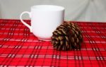 Warm Drink, White Mug And Pine Cone On Red Table Cloth (front Fo Stock Photo