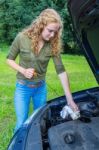 Woman Investigates Car Oil Level With Dipstick Stock Photo