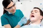 Pretty Dentist Cleaning Gums Of Patient Stock Photo