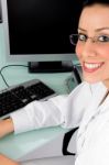 Female Doctor Seated Beside Desktop Stock Photo