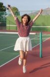 Asian Woman In Sport Tennis Course Jumping With Happiness Emotion Stock Photo