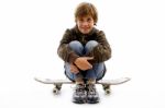Front View Of Boy Sitting On Skateboard Stock Photo