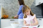 Child Drawing With Crayons, Sitting At Table In Kitchen At Home Stock Photo