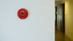 Red Fire Alarm On Wall Beside Walkway In Condominium Stock Photo