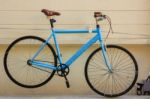 Blue Bicycle Hanging On Pale Yellow Cement Wall Stock Photo
