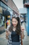 Younger Asian Woman Looking To Read Message On Smart Phone And With Happiness Emotion Stock Photo