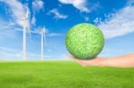 Green Grass Field With Wind Turbine And Hand Holding Green Grass Stock Photo