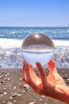 Hand Holding Glass Sphere At Beach And Sea Stock Photo