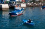 Man Rowing A Fishing Boat To Side Of Harbour In Tenerife Stock Photo