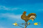 A Cockerel Wind Vane Against Blue Sky Stock Photo