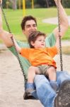 Father Enjoying Swing Ride With His Son Stock Photo
