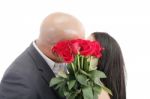 Two Young Dates Kissing Behind A Bouquet Of Red Roses Stock Photo