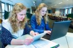 Two Dutch Girls Working On Computer And Tablet In Computer Class Stock Photo
