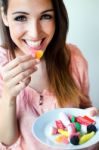 Cute Young Woman Eating Jelly Candies With A Fresh Smile Stock Photo