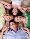 Happy Family Of Four Lying On The Carpet Stock Photo