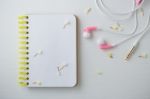 Notebook With Flowers And Earphones On White Desk Stock Photo