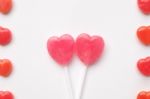Pink Valentine's Day Heart Shape Lollipop With Small Red Candy In Cute Pattern On Empty White Paper Background. Love Concept. Colorful Hipster Style. Knolling Top View Stock Photo