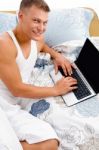 Man Working On Laptop In Bed Stock Photo